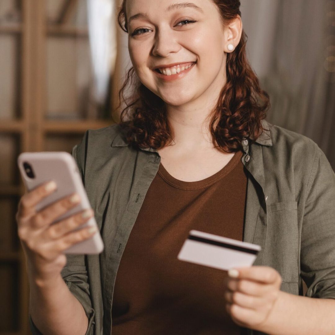 smiley-woman-using-credit-card-smartphone-home smiley-woman-using-credit-card-smartphone-home